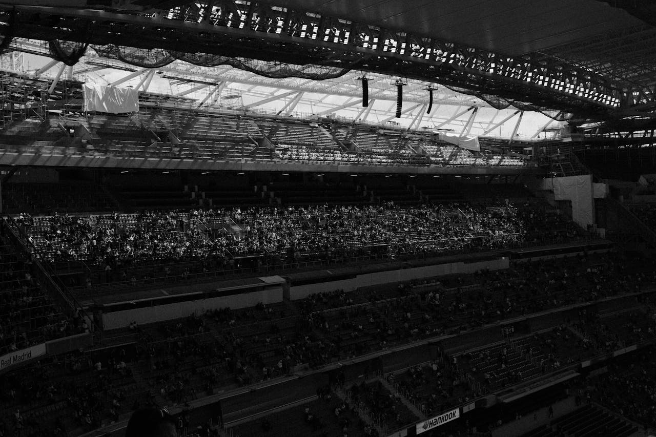 A dynamic black and white image capturing the atmosphere of a crowded soccer stadium with spectators.